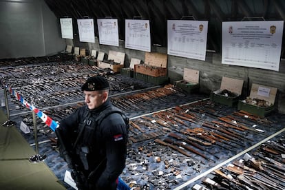 A Serbian police officer stands in front of weapons confiscated in the latest government disarmament action at a police depot near Smederevo, some 40km south of the capital Belgrade, on May 14, 2023.