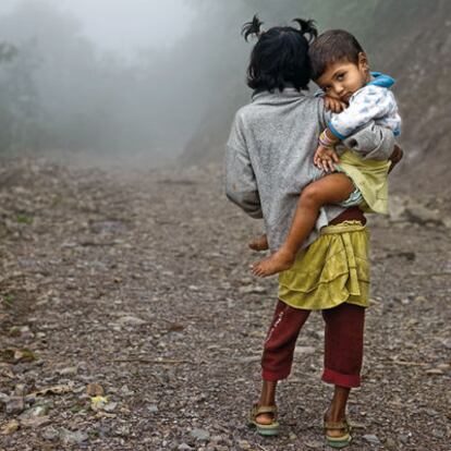 Santoshi B.K., de ocho años, posa con su pequeña hermana Rupa, de cuatro, en una brumosa montaña cercana a la ciudad de Dharan. Forman parte de una familia de siete miembros que vive en un poblado-cantera a la orilla de un río. De allí sacan piedras para machacarlas y vender el resultado como grava. Santoshi ayuda a su madre cuidando de sus hermanos y, cuando puede, martilleando las piedras.