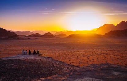 Varias personas observan el amanecer en el desierto jordano de Wadi Rum.