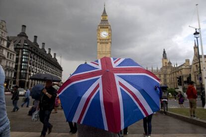 Una persona pasea en las inmediaciones del Parlamento Británico con la bandera de Reino Unido.
