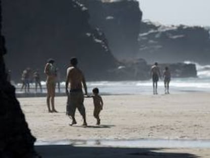 Varias personas pasean bajo el sol en la playa de las Catedrales de Lugo. EFE/Archivo