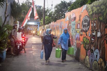 Unas vecinas en el kampung Kedondong, en Surabaya. A la izquierda de la imagen, los artistas X-Go y Brian 'Vark', sobre la moto.