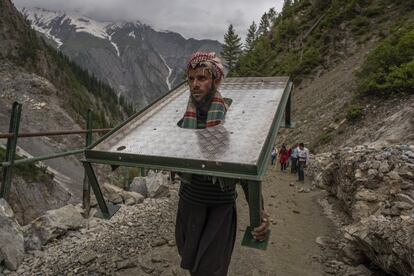 Un peregrino carga con una peana a sus hombros en su camino a la cueva sagrada de Amarnath.