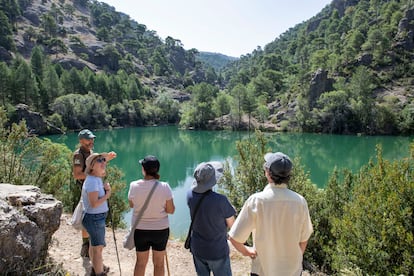 El guía Jesús Ruiz, a la izquierda, da explicaciones a unos visitantes en las inmediaciones de una laguna, en el Parque Natural de las Sierras de Cazorla, Segura y Las Villas.