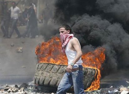 Un miliciano suní opuesto a Hezbolá quema neumáticos en una barricada para bloquear la autopista que une Beirut con la ciudad costera de Jiyeh.