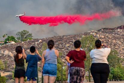 Para tratar de contener el siniestro, el Departamento de Bomberos del Condado de Riverside, ha desplegado  seis aviones cisterna y cuatro helicópteros. En la imagen, residentes de Hemet observan a un avión rociar retardante de fuego sobre el poblado, el 6 de septiembre de 2022. 