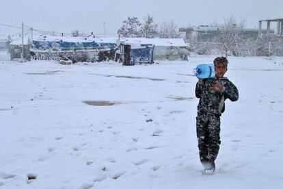 Un niño sirio camina en medio de una tormenta cargando una garrafa de agua en un campamento de refugiados en el valle de Bekaa (Líbano). 