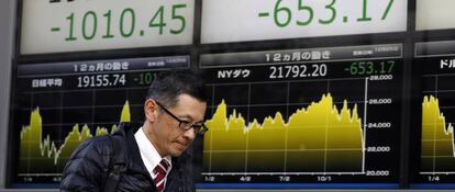 Un peatón pasa delante de unos paneles con las cotizaciones del índice de la Bolsa japonesa, el Nikkei 225.