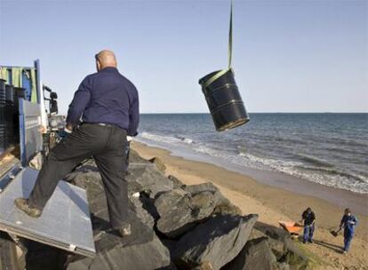 Operarios de la refineria Cepsa-La Rabida, de la factoría de Palos de la Frontera (Huelva), descargan bidones en la playa del espigón para recojer el crudo vertido accidentalmente este jueves.