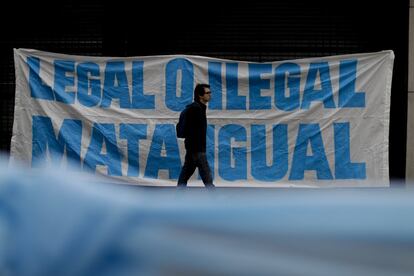Un hombre pasa frente a una pancarta que dice "legal o ilegal, mata igual", colocado frente al Senado en Buenos Aires (Argentina). 