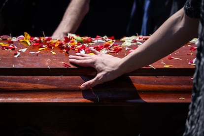 Un familiar de Joan Turner se acerca al féretro mientras se realiza el funeral en el Cementerio General, en Santiago.