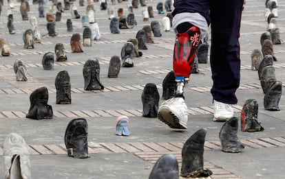 Un soldado colombiano, víctima de una mina antipersona, camina entre los más de 9.000 zapatos partidos que se han dispuesto en la plaza Simón Bolívar de Bogota, en recuerdo de las víctimas colombianas de este arma. Hoy se celebra el Día Internacional de las Víctimas de las minas antipersona.