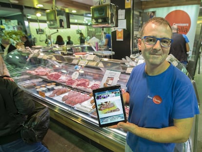 Un carnicero de Barcelona muestra la aplicación para la venta en internet, en 2017.