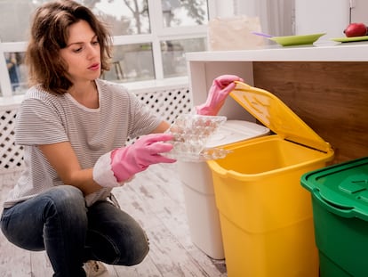 Una chica separa un envase plástico en la cocina de su casa.