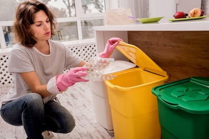 Una chica separa un envase plástico en la cocina de su casa.