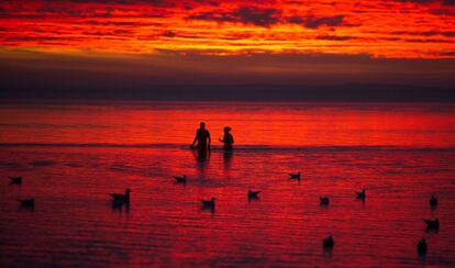 Dos personas se bañan en el mar al amanecer, en Stralsund (Alemania).