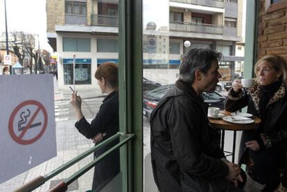 Una mujer fuma en la puerta de un establecimiento hostelero en Burgos el primer día de la entrada en vigor de la ley antitabaco.