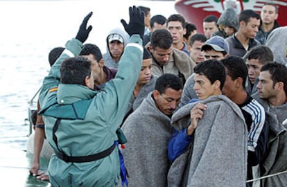 Un guardia civil da instrucciones a los inmigrantes que llegaron ayer a Algeciras en una patera.