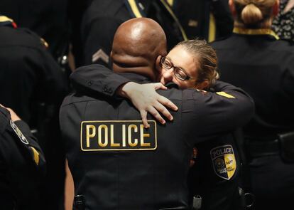 La oficial de policía Misty McBride (d) es abrazada por un compañero a su llegada al memorial situado en el Morton H. Meyerson Symphony Center, Dallas.