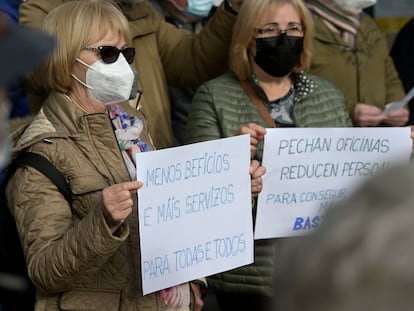 Dos mujeres sostienen unas pancartas en un acto simbólico de denuncia de la exclusión financiera en Galicia, a 7 de febrero de 2021, en A Coruña, Galicia (España).