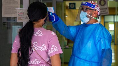 Un sanitario le mide la temperatura a una señora en la entrada del centro de salud Puerto Bonita en Madrid. Andrea Comas