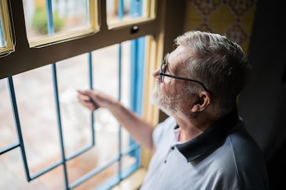 Un hombre mira contemplativamente por la ventana.