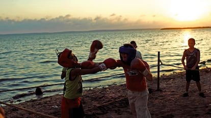 Durante el ocaso en una playa de Cienfuegos, unos muchachos hacen boxeo.