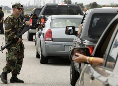 Un miembro de la Guardia Nacional de Estados Unidos comprueba los pases de quienes han iniciado su camino de regreso a las ciudades desalojadas