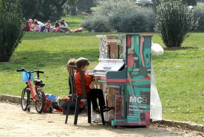 Dos niños tocando uno de los pianos en el parque de la Ciutadella.