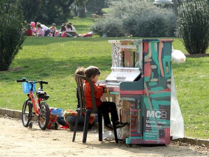 Dos niños tocando uno de los pianos en el parque de la Ciutadella.