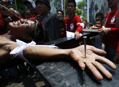 Un penitente hace muecas de dolor mientras está siendo clavado en una cruz de madera durante la recreación de la muerte de Jesucristo el Viernes Santo en San Fernando (Filipinas).