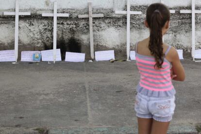 Una niña mira las cruces depositadas ante la escuela en memoria de las víctimas.