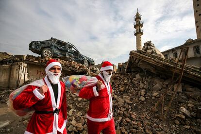 Dos jóvenes iraquiés, disfrazados de Papá Noel, reparten regalos por las calles de la antigua ciudad de Mosul. 