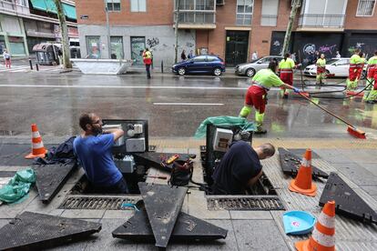 Dos operarios trabajan en la calle Antonio López. Varios bloques se han quedado sin conexión a internet porque el cableado, que va por debajo de la acera, está empapado.
