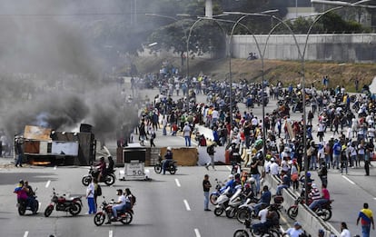 Manifestantes voltean un vehículo en una de las principales vías de la capital venezolana, durante una de las protestas en contra de Nicolás Maduro.