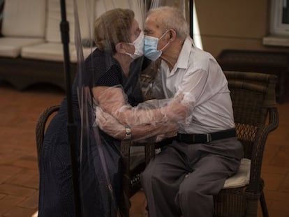 Una mujer abraza y besa a su marido a través de una pantalla de plástico para evitar contraer el coronavirus en una residencia de ancianos en Barcelona.