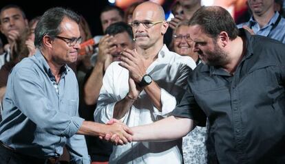 Artur Mas y Oriol Junqueras se dan la mano, en el centro, Raul Romeva.