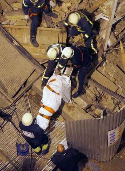 Los bomberos retiran el cadáver de la anciana.