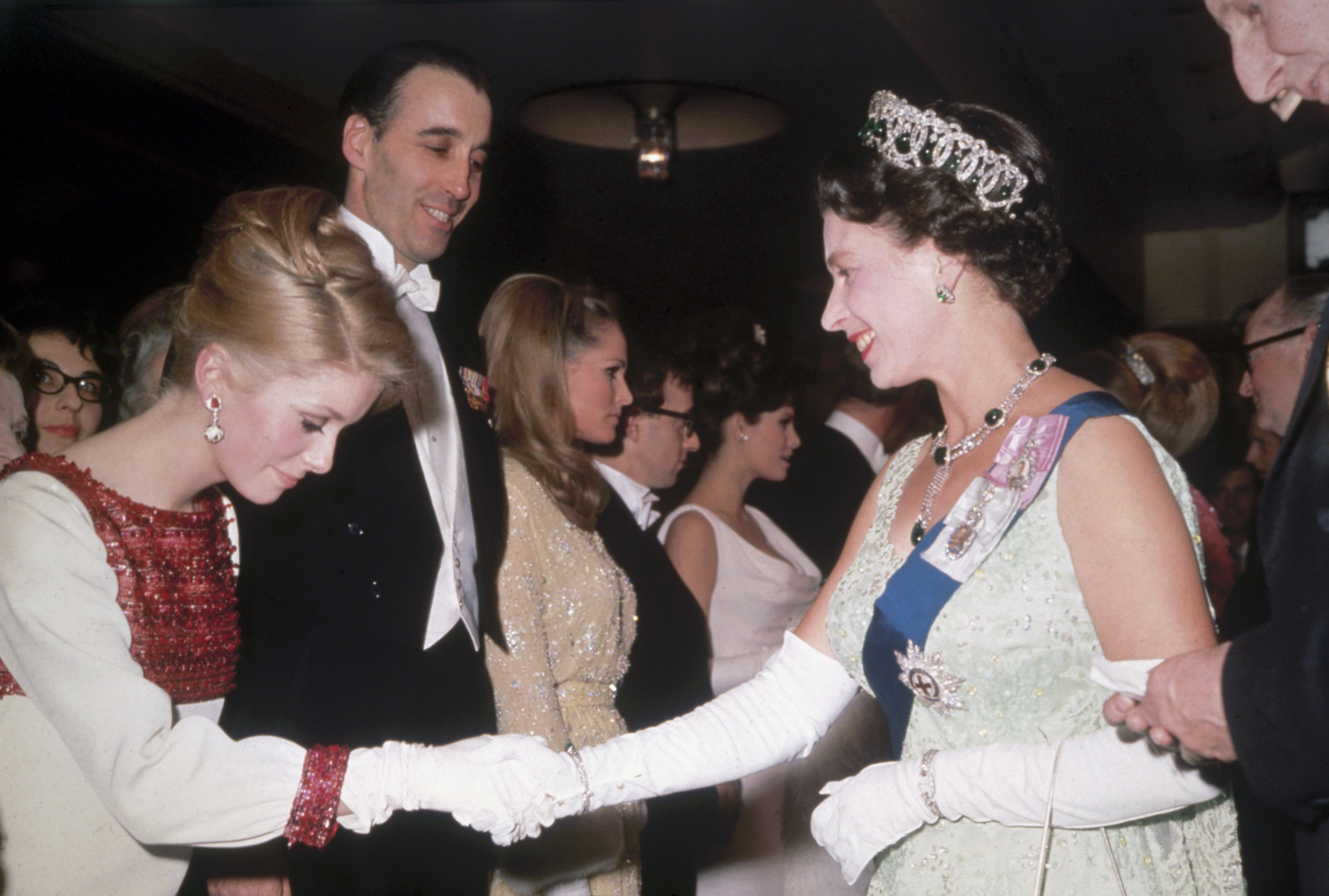 Isabel II saluda a Catherine Deneuve en Londres en 1966. Al fondo están Christopher Lee, Ursula Andress, Woody Allen y Raquel Welch.