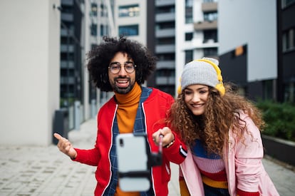 Young couple with smartphone making video outdoors on street, tik tok concept.