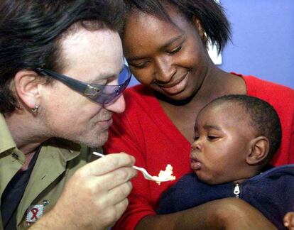 Bono da de comer a Thomas Qubile, un niño de 11 meses enfermo de sida, en presencia de su madre, Mpumelelo, en una clínica de atención prenatal a afectados por el virus del VIH del hospital Chris Hani Baragwanath de Soweto (Sudáfrica) en mayo de 2002.