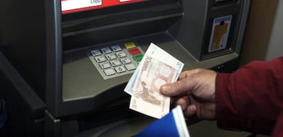 Un hombre retira euros de un cajero autom&aacute;tico.