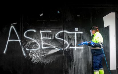 Una trabajadora elimina una pintada de "asesinos" en la fachada del estadio municipal El Plantío, en Burgos.