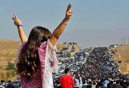 Una adolescente iraní sin velo hace el signo de la victoria ante un cortejo de iraníes que se dirigían al cementerio de Saqqez, en el Kurdistán iraní,  donde está enterrada Yina Mahsa Amini, el 26 de octubre de 2022.