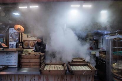 Un vendedor espera a los clientes en un puesto de 'dumplings' en un mercado de Seúl (Corea del Sur).