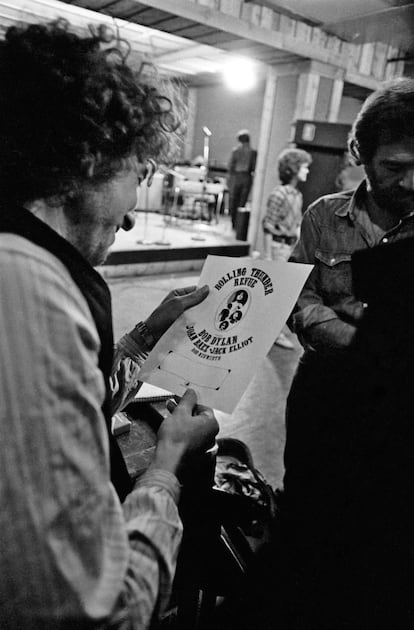 Bob Dylan observa um dos cartazes da turnê The Rolling Thunder Revue.