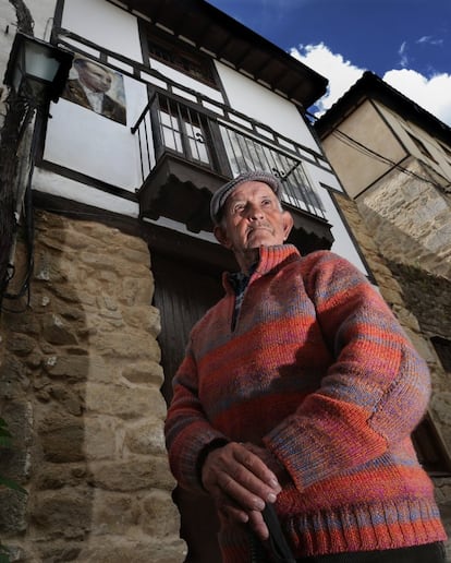 Francisco Maillo Calama, de 84 años, nació sin audición y, a diferencia de otros decidió quedarse junto en Mogarraz. Ahora, con la ayuda de un bastón de senderismo, se pasea por las calles empedradas y recuerda, con el lenguaje de signos, las vidas de cada retratado. En la imagen, Maillo Calama posa bajo su pintura.