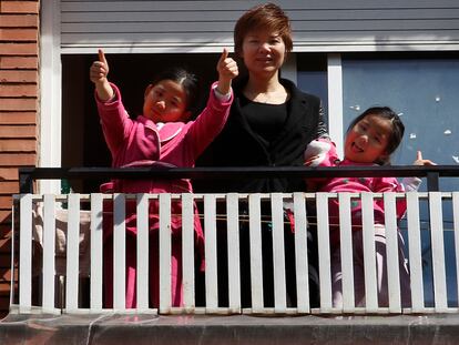 Wei Chen y sus hijas saludan desde el balcón de su piso de Barcelona, donde llevan una semana confinadas.