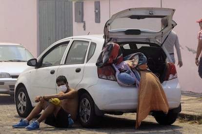 Un hombre descansa junto a su coche mientras se prepara para salir de su casa durante un incendio forestal en las laderas alrededor de Quito.