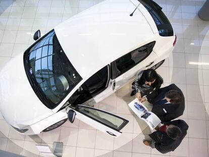 Un vendedor muestra un vehículo a una pareja en un concesionario.